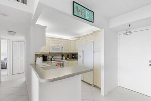 A modern kitchen with white cabinets, a granite countertop, and a microwave.