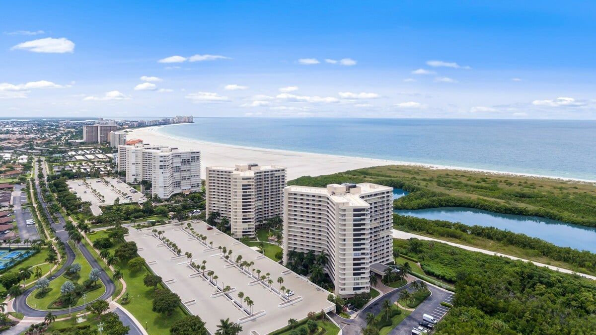Ein Küstenhotel mit mehreren Hochhäusern, einem Parkplatz und Blick auf den Strand.