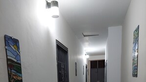 Kapea käytävä, jonka seinät ovat valkoiset, lattia on laatoitettu ja siellä on ruukussa oleva kasvi.