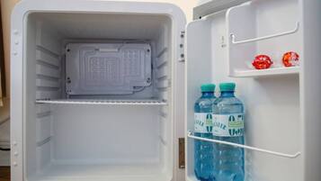 Ein offener Kühlschrank mit Wasserspender und zwei Wasserflaschen auf der Türablage.