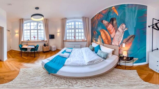 Une chambre à coucher moderne avec un lit aux lignes courbes, un bureau et une grande fenêtre.