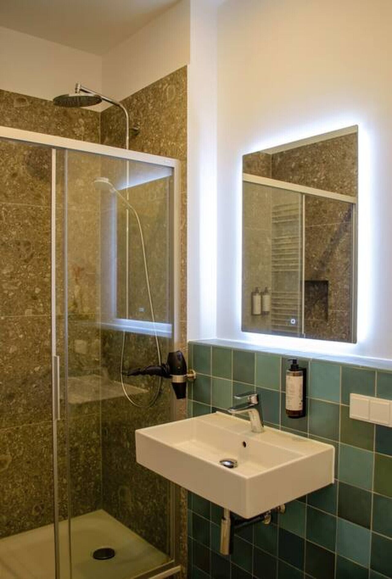 A bathroom with a glass-enclosed shower, a white sink, and a mirror above it.
