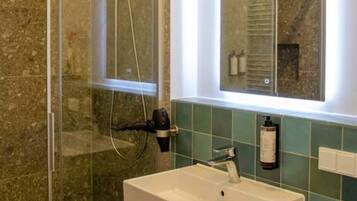 A bathroom with a glass-enclosed shower, a white sink, and a mirror above it.