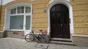 A building with a large arched window and a door with a sign above it. A bicycle is parked in front of the door. - Homely Stay Studio1 - Your place to relax (München)