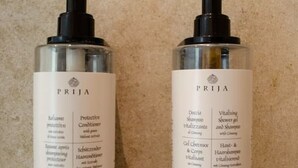 Dos botellas de productos capilares PRIJJA sobre una superficie texturizada.