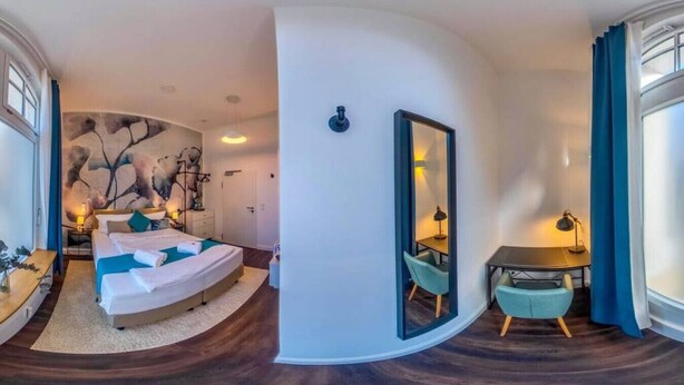 Una habitación de hotel moderna con una cama curvada, un escritorio y un espejo grande.
