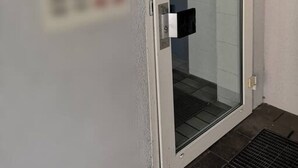 A door with a glass panel, a keypad lock, and a small sign on the wall. - Homely Stay Studio6 - Modern with feel-good factor (München)