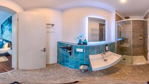 Un baño moderno con un lavamanos curvo, una cabina de ducha de cristal y un espejo sobre el lavamanos.