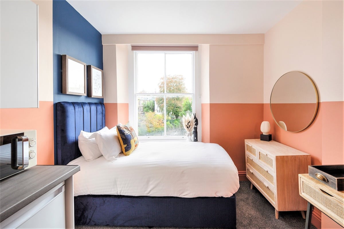A bedroom with a bed, dresser, and a large window.