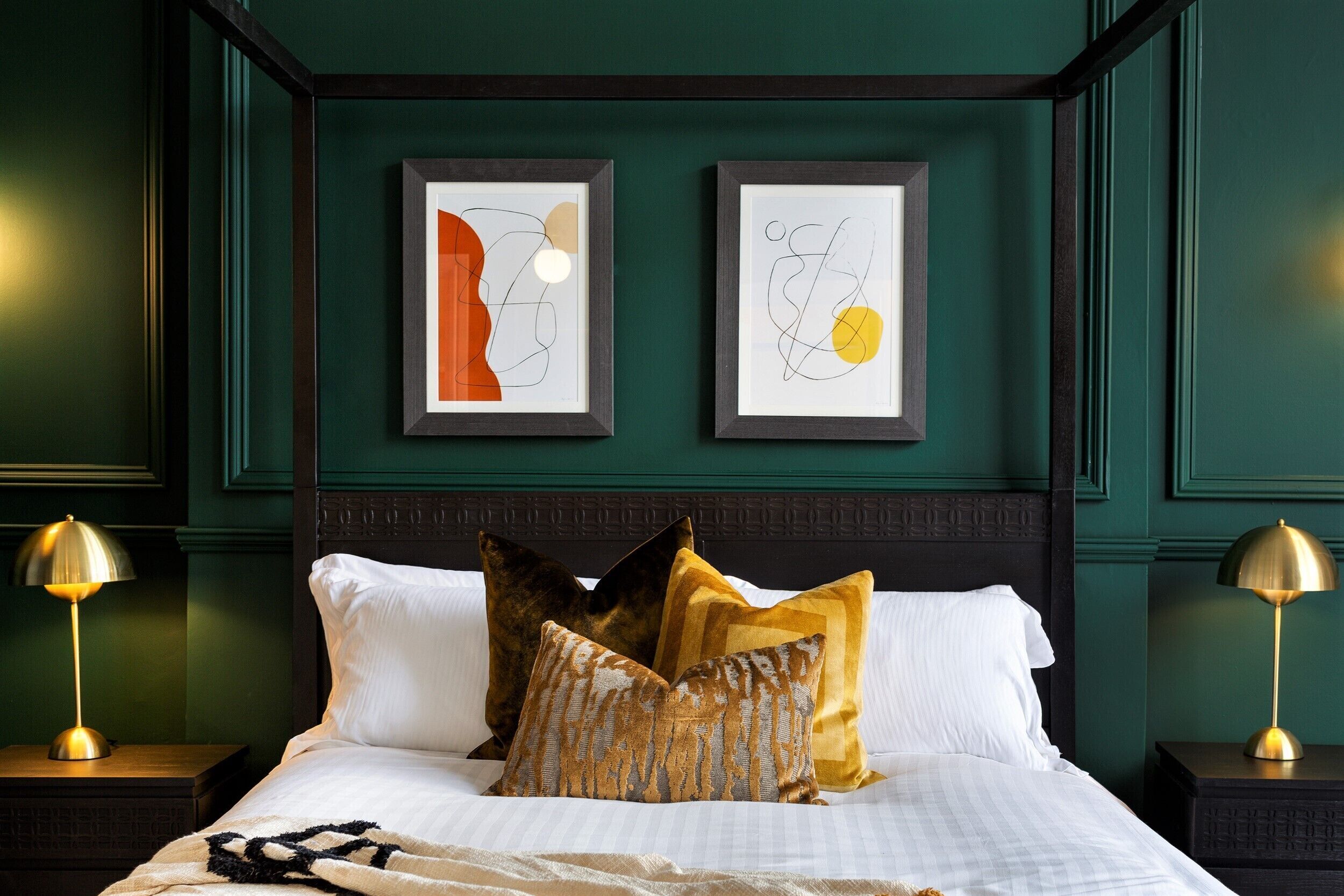 A neatly made bed with white linens and patterned pillows, a dark wooden headboard, and two bedside tables with lamps.