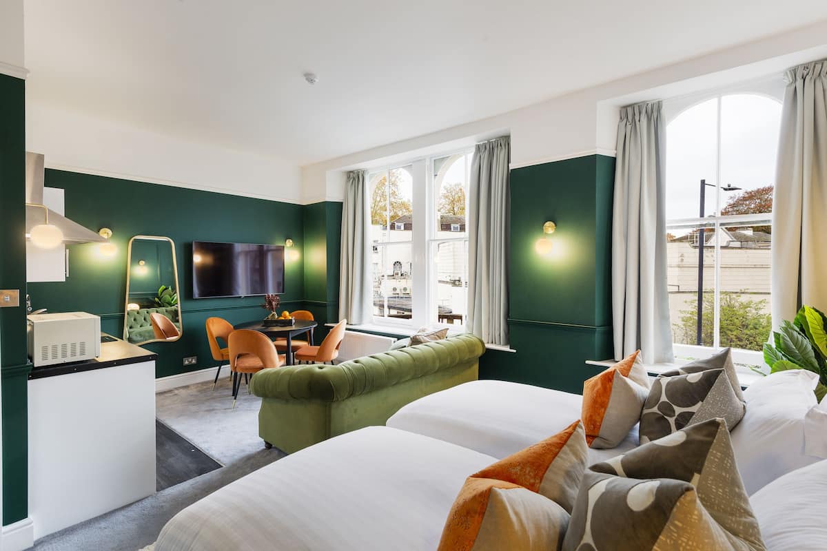 A hotel room with a bed, a sofa, a desk, and a TV.