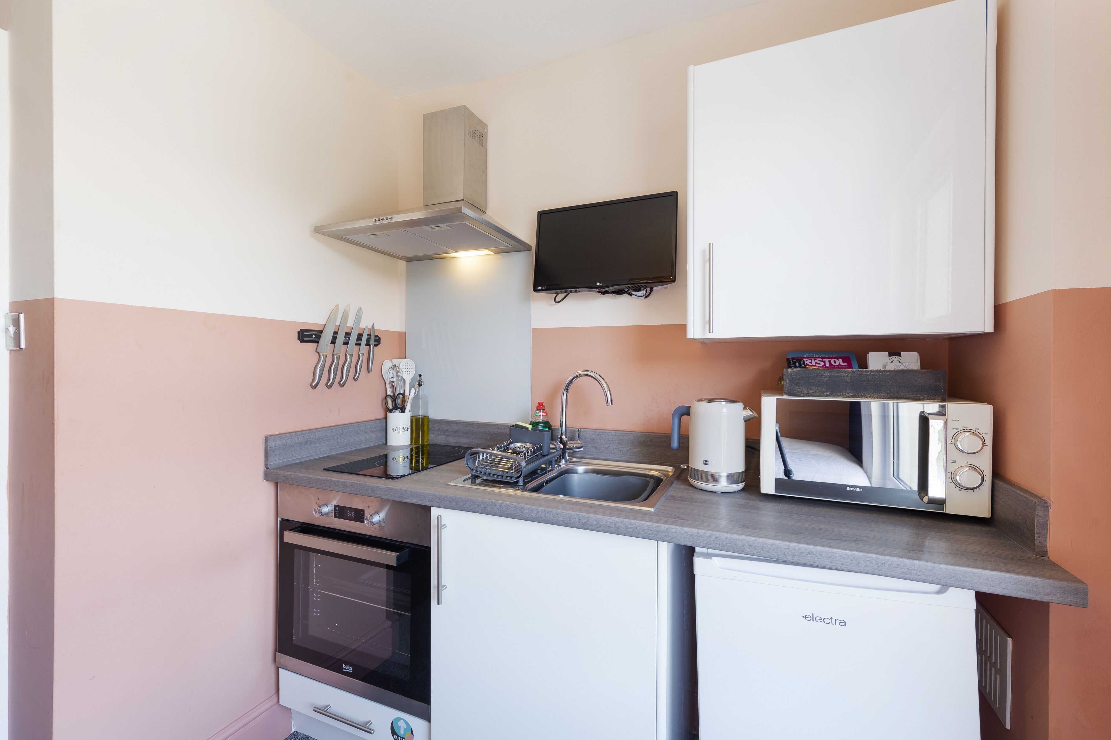 A compact kitchen with a microwave, toaster, sink, and a small oven.