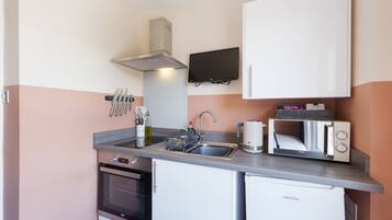 A compact kitchen with a microwave, toaster, sink, and a small oven.