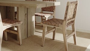 Ein Essbereich mit einem Holztisch und Stühlen, einem gewebten Teppich und einer Wand, die mit verschiedenen Keramikplatten und Tonwaren verziert ist.