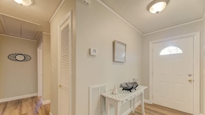 A hallway with a white door, a radiator, a small table with a decorative item, and a wall-mounted thermostat. - ★ Good Vibes Ranch ★ Walk to Zoo | Pet Friendly (West Columbia)