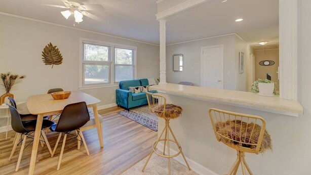 A dining area with a wooden table and chairs, a blue sofa, and a ceiling fan. - ★ Good Vibes Ranch ★ Walk to Zoo | Pet Friendly (West Columbia)