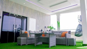 A modern living room with a grey sofa set, a glass-top coffee table, and a hanging chair. - Luxury Apartment With sea View in Lekki/ajah (Lekki)