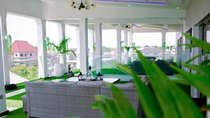 A modern living room with a large sectional sofa, a coffee table, and a TV. There are potted plants and a view of buildings outside. - Luxury Apartment With sea View in Lekki/ajah (Lekki)