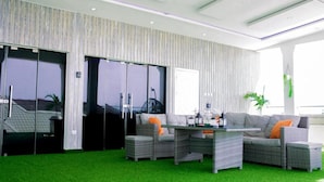 A modern indoor space with a green artificial turf floor, wicker furniture, and a glass door leading to a balcony. - Luxury Apartment With sea View in Lekki/ajah (Lekki)