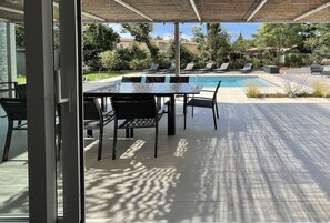 An outdoor patio with a pool, lounge chairs, and a dining area with a table and chairs.