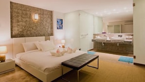 A modern hotel room with a large bed, a bench, a glass shower enclosure, and a separate bathroom with a vanity and sink. - Siam Royal View Pool Villa by PSR ASIA (Ko Chang)