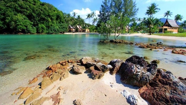 A tropical beach with clear waters, rocky shoreline, and palm trees. - Siam Royal View Pool Villa by PSR ASIA (Ko Chang)
