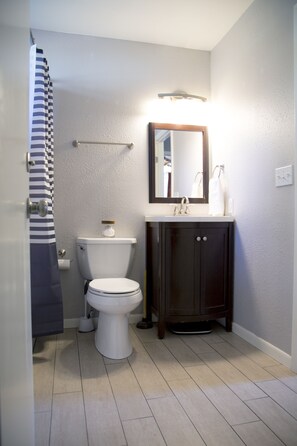 Bathroom features a toilet, sink, and shower with a towel rack and striped shower curtain.