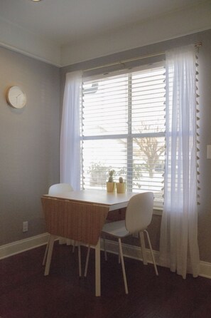 Enjoy meals in this cozy dining area with a table for four, a clock on the wall, and a view through the large window.