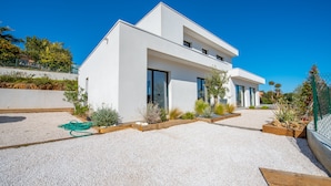 A modern two-story house with a white exterior, large windows, and a gravel driveway. - Contemporary villa with pool and sea view for 10 people (Cavalaire-sur-Mer)