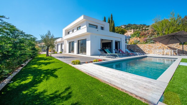 A modern house with a swimming pool, a wooden deck, and a well-maintained lawn. - Contemporary villa with pool and sea view for 10 people (Cavalaire-sur-Mer)