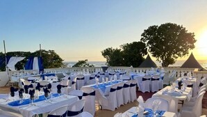 An outdoor dining area with tables set for a meal, overlooking a body of water. - Dela de-Rose Guest House negril Jamaica (Negril)