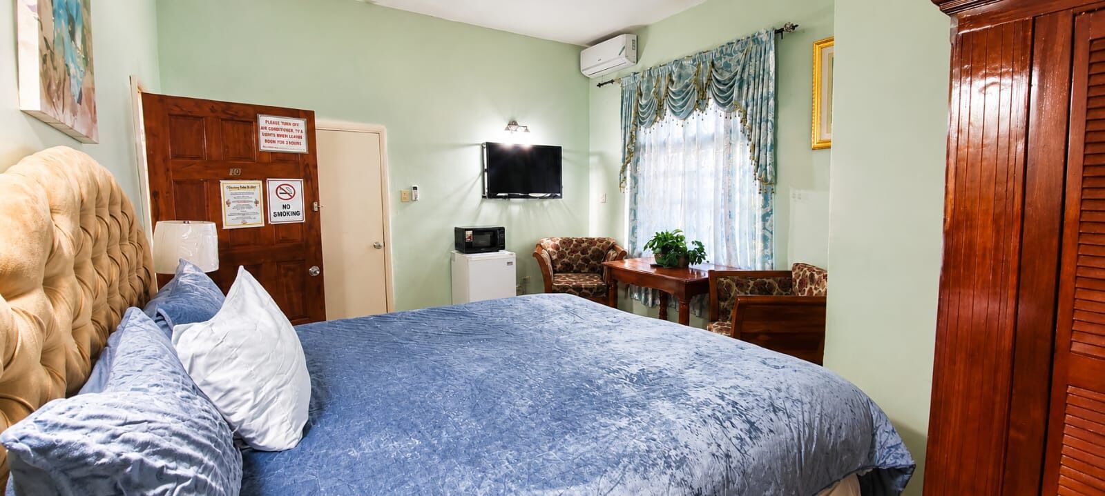 Ein Schlafzimmer mit Bett, Schreibtisch, Stuhl, Fernseher und einer Tür mit einem Schild.