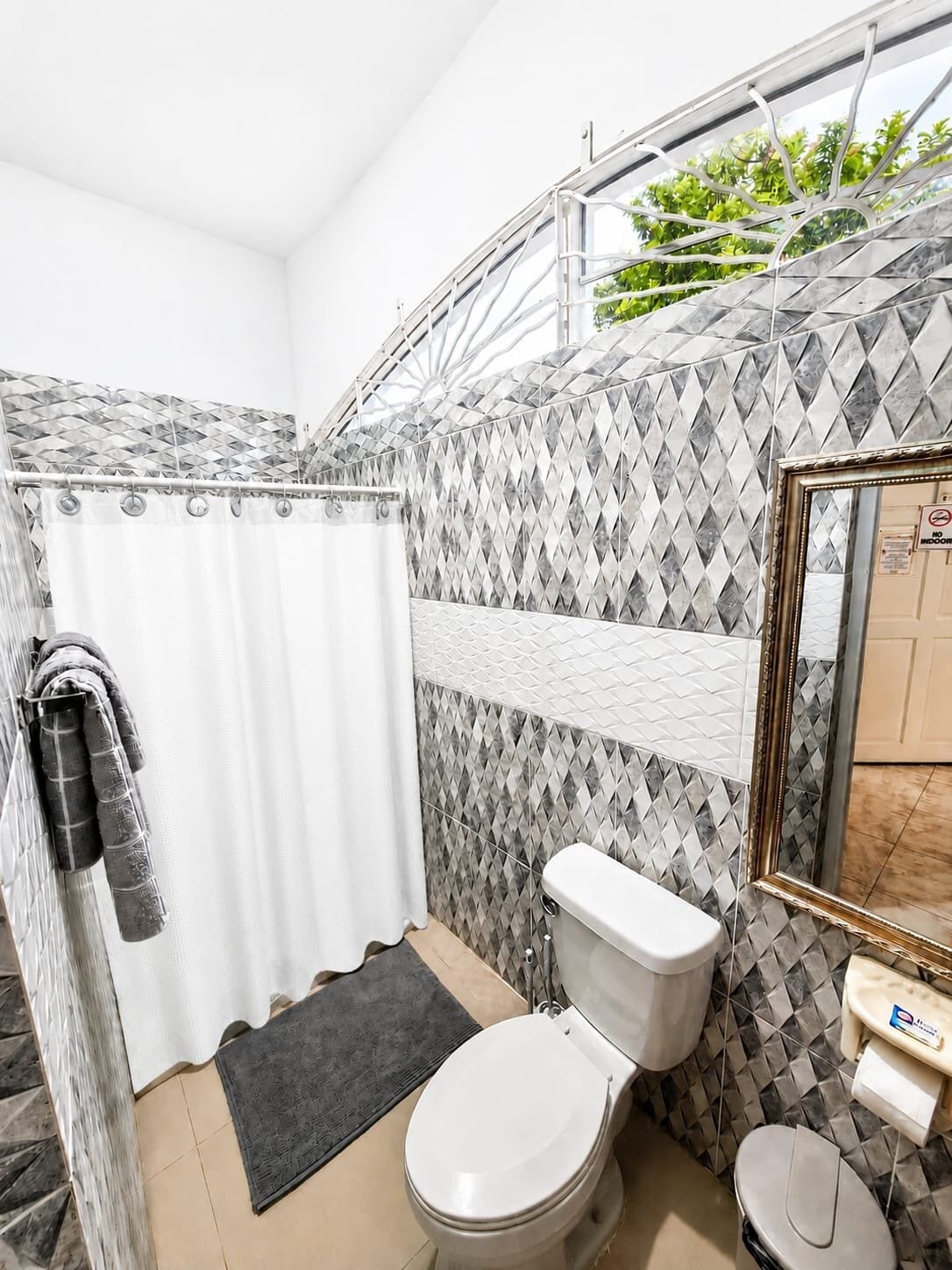 A bathroom with a shower, toilet, and a mirror.