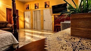 A living room with a ceiling fan, a wooden coffee table, a patterned rug, and a potted orchid. - Dela de-Rose Guest House negril Jamaica (Negril)