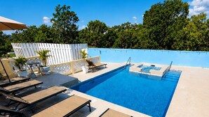 A pool area with lounge chairs, a small table, and a pool with a blue border. - Dela de-Rose Guest House negril Jamaica (Negril)