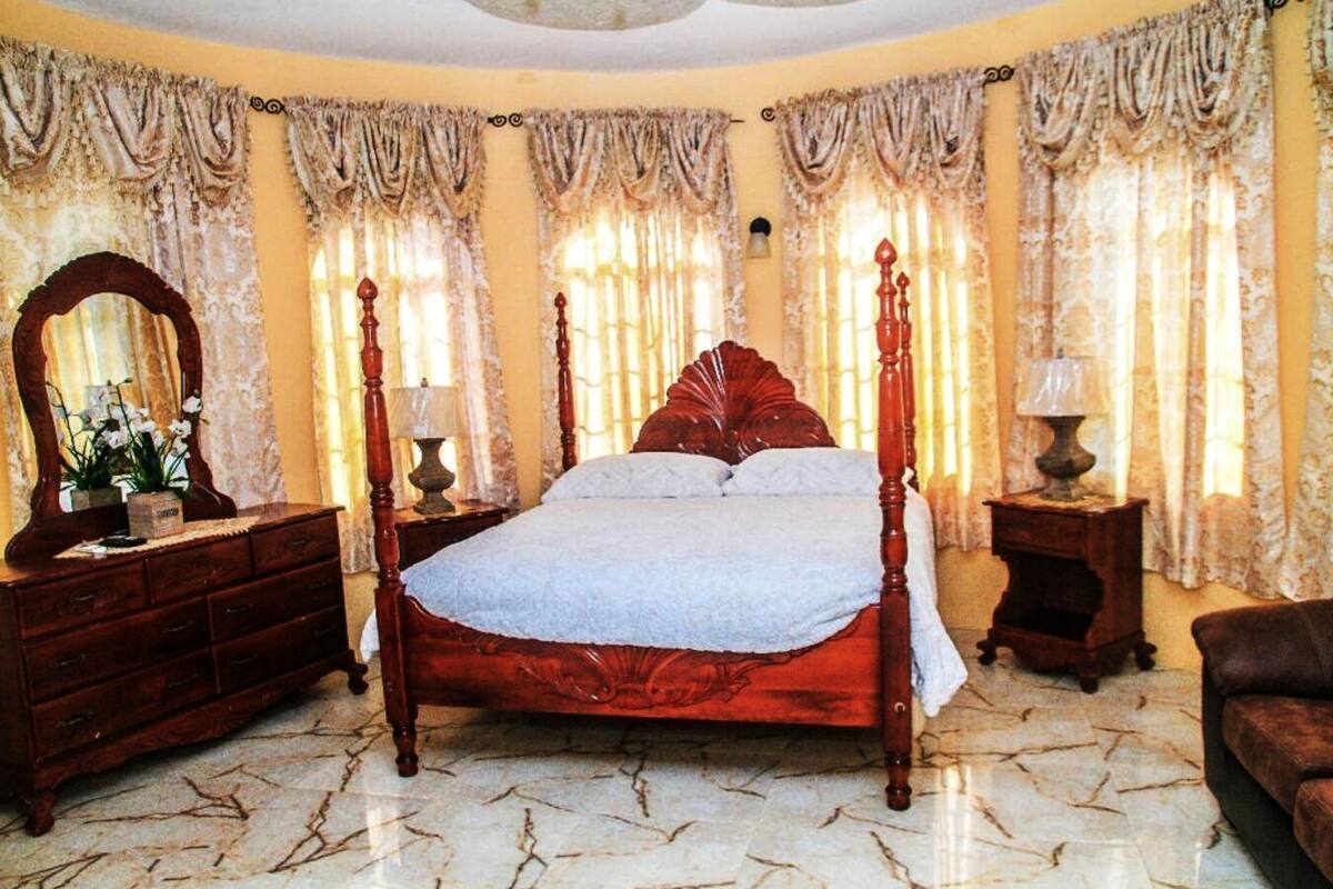 Une chambre à coucher avec un lit à baldaquin, une commode en bois, un miroir et une lampe.