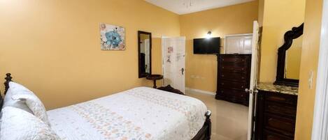 A bedroom with a bed, dresser, mirror, and artwork on the wall.