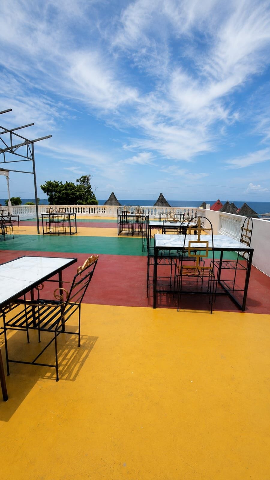 A rooftop terrace with outdoor seating, a white table, and a view of the ocean.