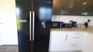 Una cocina moderna con un refrigerador negro, dispensador de agua, microondas y cafetera.