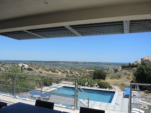 A pool area with a view of the sea and distant landscape.