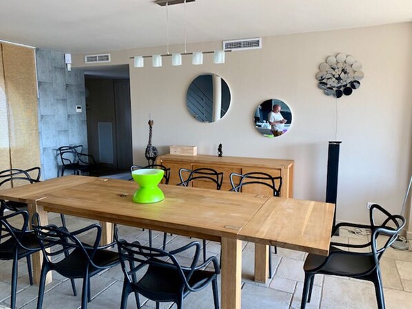 A dining area with a wooden table and black chairs, a wooden cabinet, and two round mirrors on the wall.