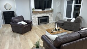 Uma sala de estar moderna com lareira, sofás de couro, uma mesa de centro e uma TV fixada na parede.