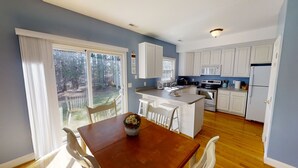 A spacious kitchen with white cabinets, a central island, and a dining area with a wooden table and chairs. - Entire Townhouse in Rock Hall (Rock Hall)