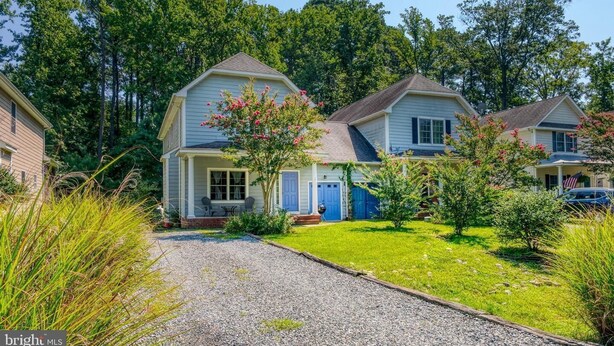 A two-story house with a front porch, a small garden, and a gravel driveway. - Entire Townhouse in Rock Hall (Rock Hall)