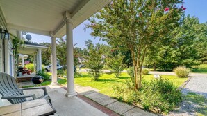 A covered porch with a grill, outdoor seating, and a well-maintained lawn. - Entire Townhouse in Rock Hall (Rock Hall)