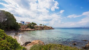Une propriété située sur la côte, offrant une vue dégagée sur la mer, un rivage rocheux et un bâtiment aux accents bleus.
