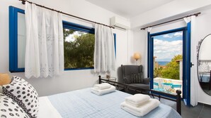 Une chambre avec un lit, une chaise, une petite table et une vue sur la mer.