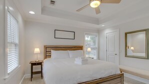 A bedroom with a wooden bed, two bedside lamps, a ceiling fan, and a large mirror on the wall. - Southern City Comfort - Huge Private Backyard (Nashville)