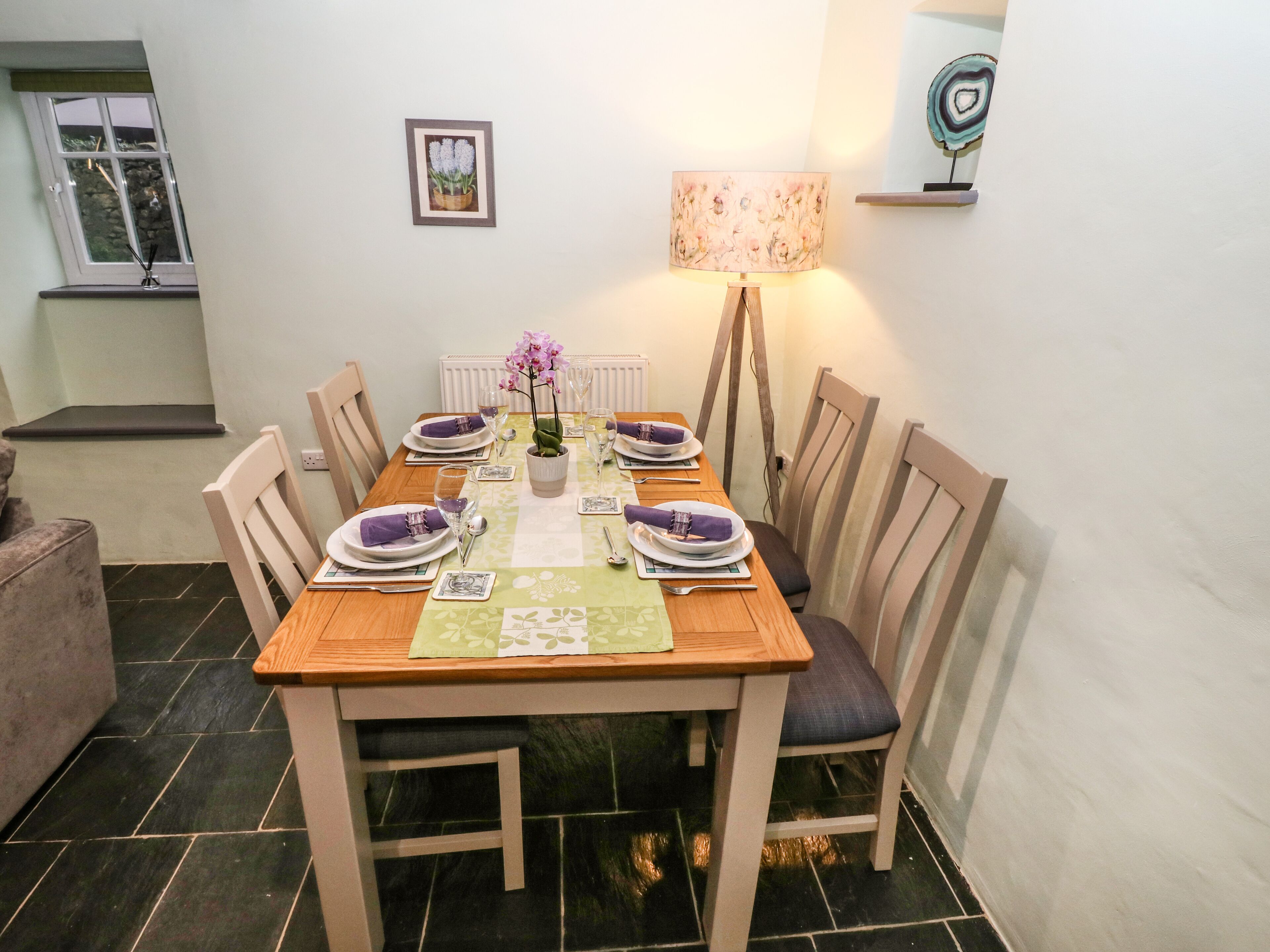 A dining table set with plates, glasses, and a vase of flowers.