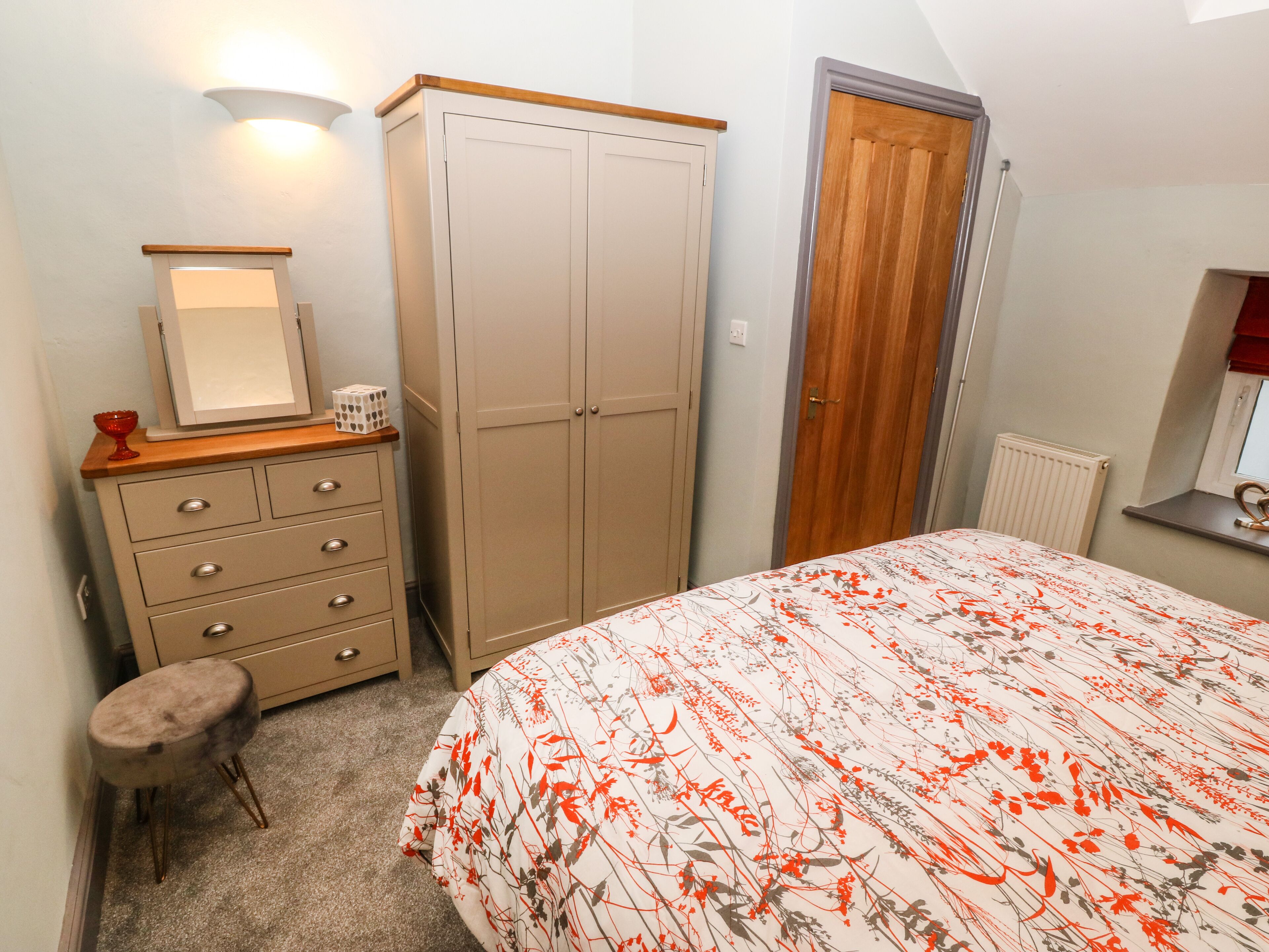 Ein Schlafzimmer mit Bett, Schminktisch, Spiegel und Kleiderschrank.
